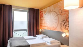 Habitación de hotel con cama, ventana con cortinas, pared con diseño decorativo y lámpara de noche.