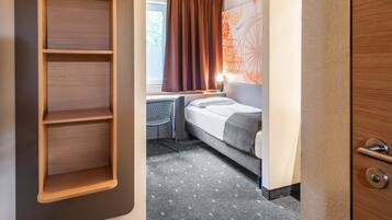 Una habitación de hotel con una cama, un escritorio y una estantería de madera.