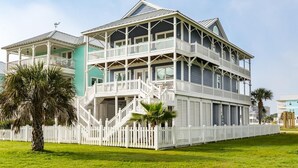 A two-story house with a balcony and a white picket fence. - Booking NOW for fall! 5 min walk to beach! Wrap @decks. Gulf Views! (Galveston)