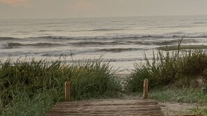 A wooden boardwalk leading to the ocean with waves in the background. - Booking NOW for fall! 5 min walk to beach! Wrap @decks. Gulf Views! (Galveston)