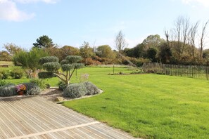 Enjoy the serene atmosphere of our expansive lawn surrounded by lush greenery and a beautifully manicured deck.