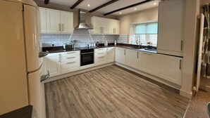 Een moderne keuken met witte kasten, een zwart aanrecht en een houten vloer.
