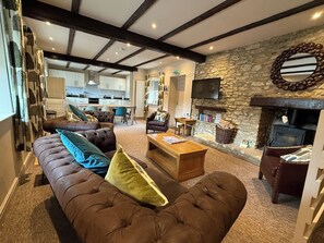 Un salon chaleureux avec un canapé marron, une table basse en bois et une cheminée en pierre.