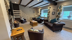 Een gezellige woonkamer met een open haard, een trap en een groot raam met gordijnen.