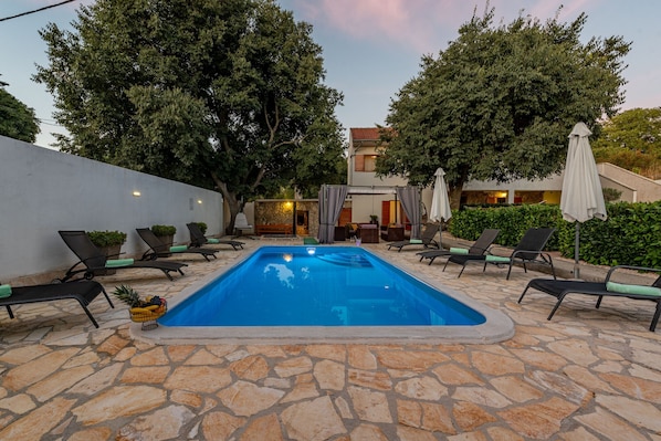 Relax by the pool surrounded by lush greenery and comfortable lounge chairs.