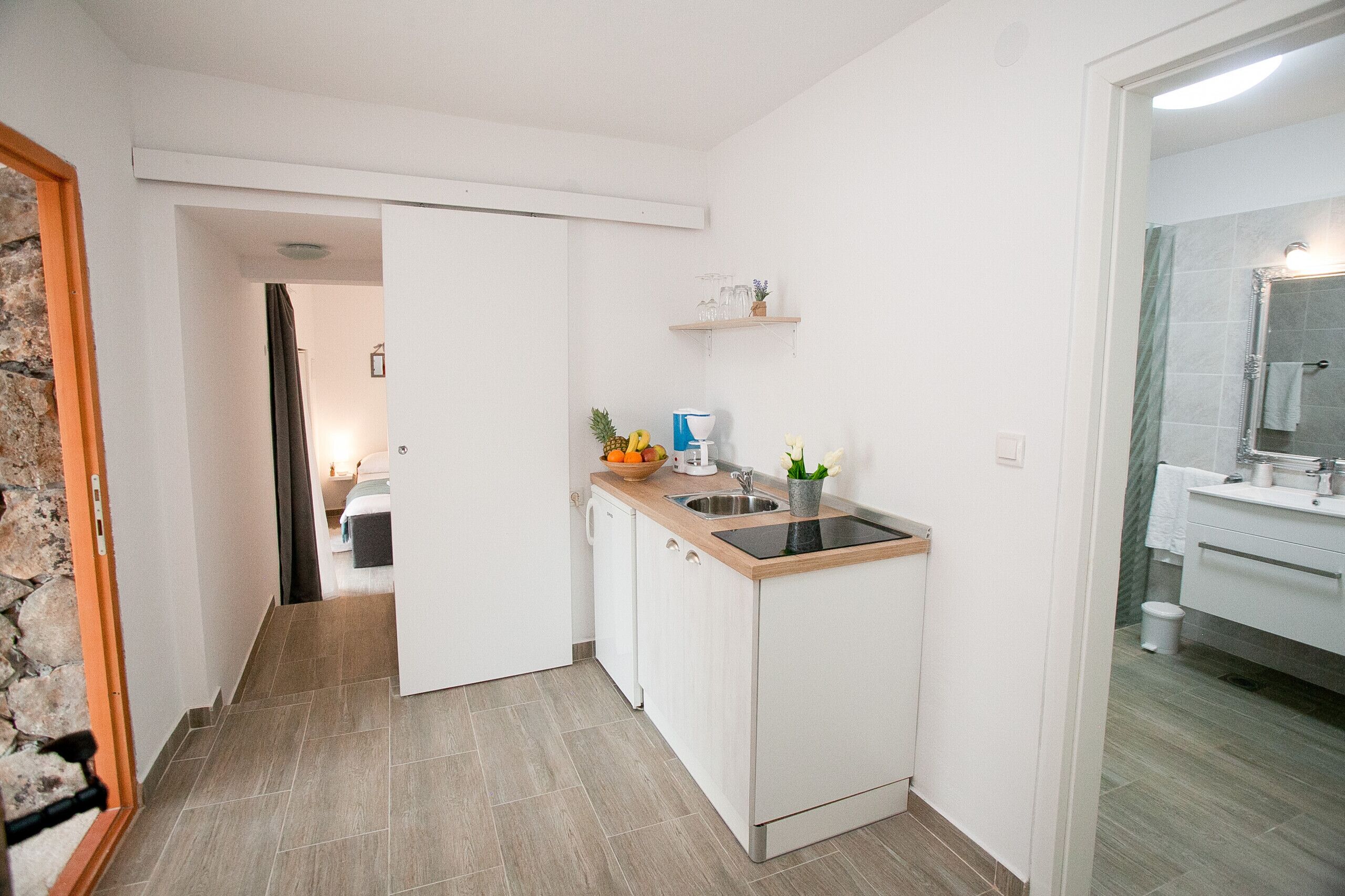 A compact kitchen with a sink, countertop, and a small countertop area with a potted plant.