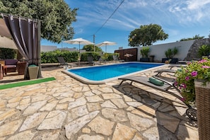 Relax by the pool surrounded by lush greenery and shaded seating.