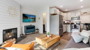 Un salon moderne avec une cheminée, une table basse en bois et un canapé.