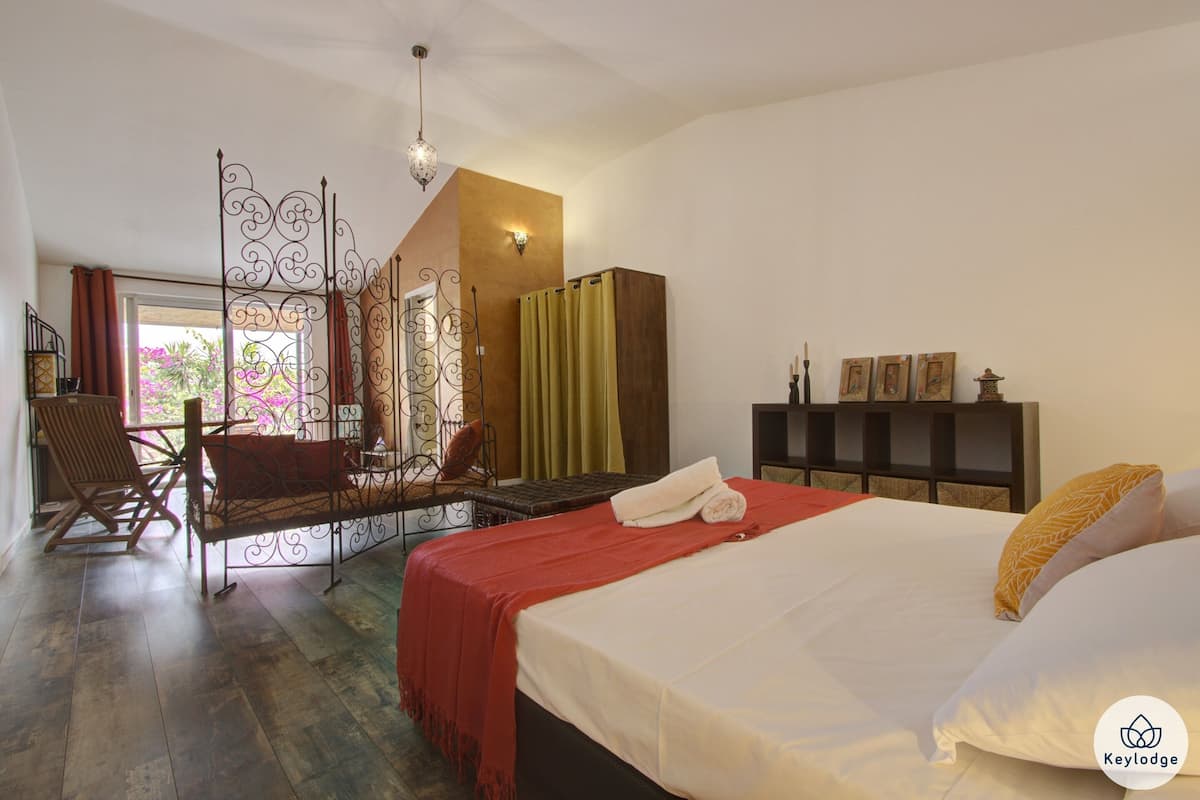 Un dormitorio con cama, sillón mecedora, armario y un separador decorativo.