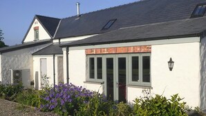 A white building with a grey roof, a chimney, and a door with glass panels. - 2 bedroom accommodation in Dwrbach, near Fishguard (Dwrbach, near Fishguard)