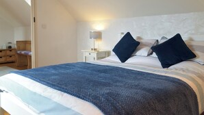 A bedroom with a bed, a bedside table, a lamp, and a mirror. - 2 bedroom accommodation in Dwrbach, near Fishguard (Dwrbach, near Fishguard)