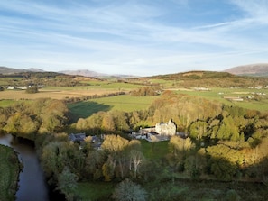 Un château entouré de champs verdoyants et traversé par une rivière.