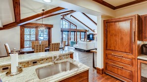 A spacious kitchen with a large island, wooden cabinets, and a high ceiling with exposed beams. - 1-#42 4BD One Willow Bridge Road (Vail)