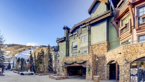 A multi-story hotel with a stone facade and balconies, located in a ski resort area with a clear view of the mountains. - 1-#42 4BD One Willow Bridge Road (Vail)