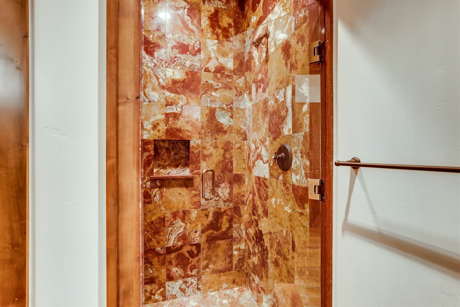 A hallway with a marble floor and a wooden door.