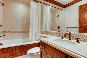 A bathroom with a white bathtub, wooden vanity, and a toilet. - 1-#42 4BD One Willow Bridge Road (Vail)