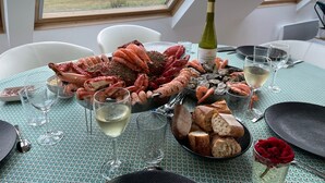 A table set with seafood, wine, and bread, overlooking a scenic landscape. - Maison des dunes, panoramic sea view and waterfront - bikes, paddles (Plouescat)
