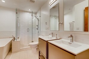 A modern bathroom with a glass-enclosed shower, a toilet, two sinks, and a bathtub. - 1-brookside 307 (Avon)