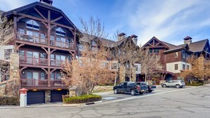 A multi-story building with a wooden facade, balconies, and a parking lot with cars. - 1-brookside 307 (Avon)