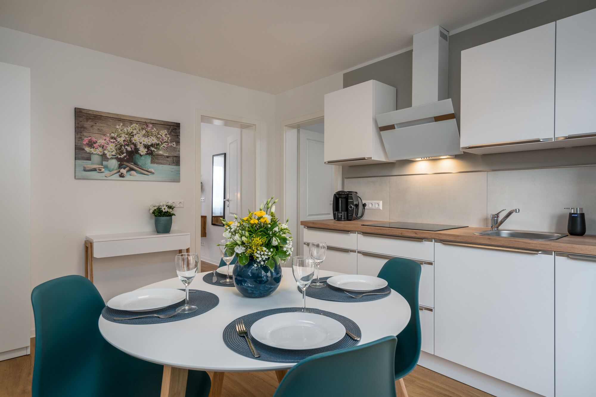 A modern kitchen with white cabinets, a coffee maker, and a sink.
