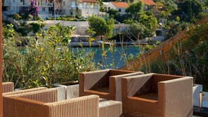 Wicker furniture on a terrace with a view of houses and a body of water. - Luxury Beachfront Villa Blue Star Brac with Pool (Milna)
