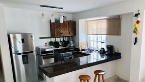 A modern kitchen with a stainless steel refrigerator, a built-in oven, a stove, and a large island with stools. - Apartment half a block from the sea (San Miguel de Cozumel)