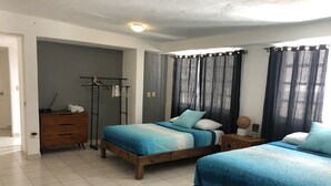 A bedroom with two beds, a wooden dresser, a coat rack, and a small table with a vase. - Apartment half a block from the sea (San Miguel de Cozumel)