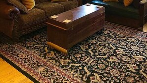 Un salon chaleureux avec un plafond en bois, deux canapés avec des coussins, une table basse et un tapis à motifs.