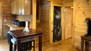 Ein Holzblockhaus-Innenraum mit Küchenbereich, einer Waschmaschine und einem Esstisch.