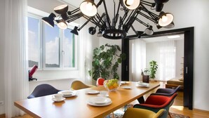 A dining area with a wooden table, colorful chairs, a chandelier, and potted plants. - Luxury Villa Castello Dubrovnik with Pool & Sauna (Dubrovnik)