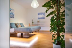Ein modernes Wohnzimmer mit einer Couch, einer Pendelleuchte und einem Blumentopf.