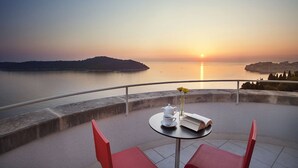 A terrace with a table set for tea, overlooking a body of water and a distant landmass during sunset. - Luxury Villa Castello Dubrovnik with Pool & Sauna (Dubrovnik)