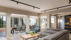 A spacious living area with a large grey sectional sofa, a wooden coffee table, and a dining area with chairs and a table.