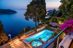 A pool with a view of the sea, surrounded by greenery and stairs leading down to the water. - Luxury Seafront Villa Dubrovnik Palace with Pool (Dubrovnik)