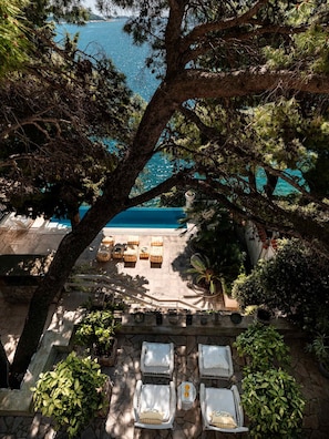 A pool area with lounge chairs and a view of the sea.