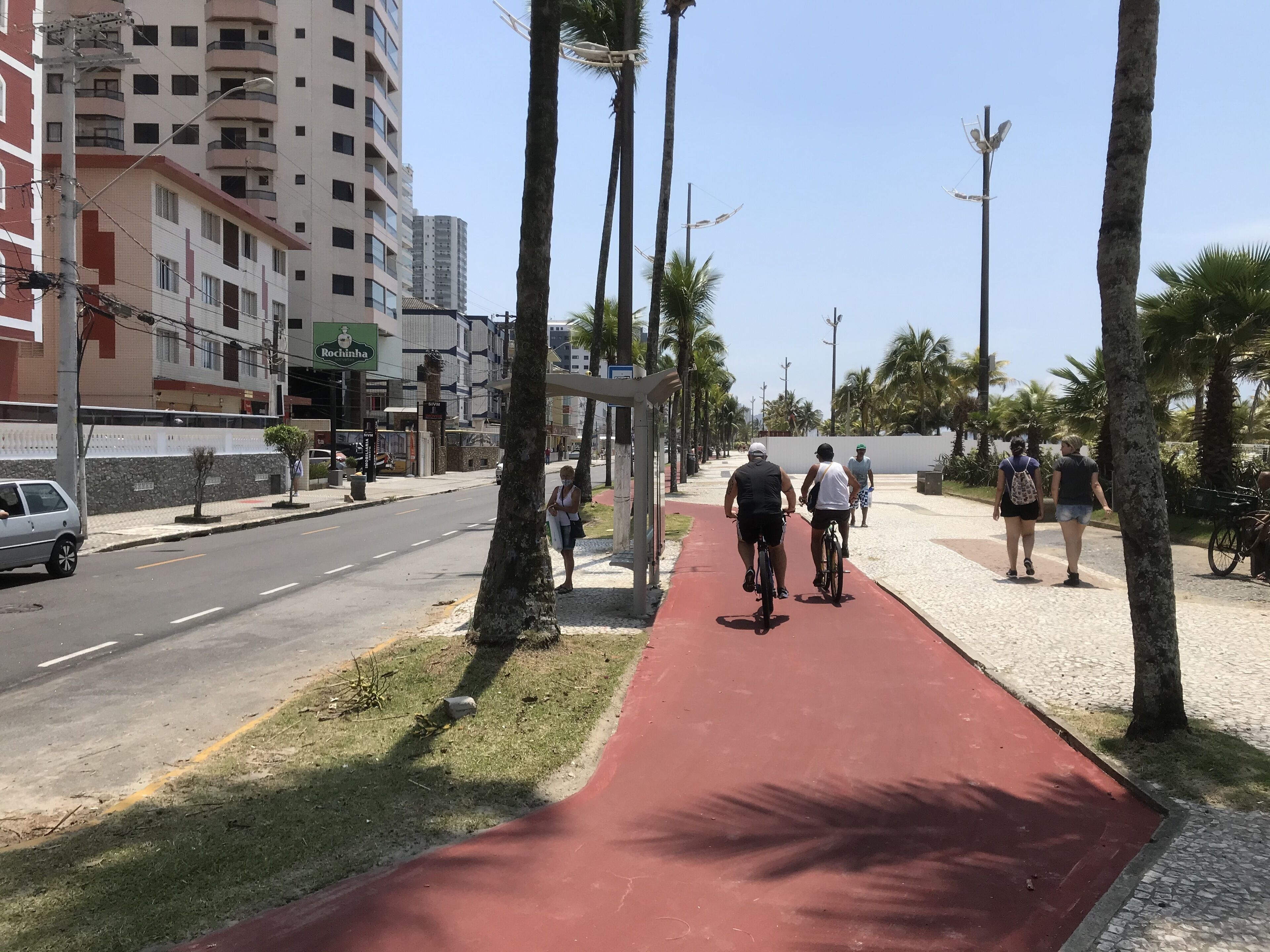 Ein roter Radweg mit Palmen, einem Bürgersteig und einem Gebäude mit der Aufschrift "Rochinha".