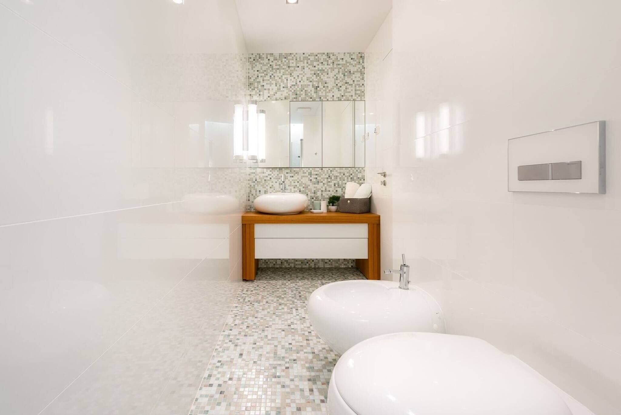 A modern bathroom with a white sink, wooden vanity, and a large bathtub.
