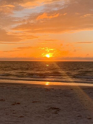Un coucher de soleil sur une plage, avec des vagues qui se rapprochent du rivage.