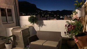 An outdoor patio area with a wicker sofa, a small table, and potted plants. - Home SEA & DREAMS OldTown I (Calp)