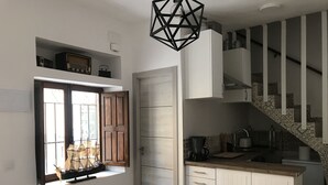 A compact kitchen with a built-in island, wooden cabinets, and a window with wooden shutters. - Home SEA & DREAMS OldTown I (Calp)