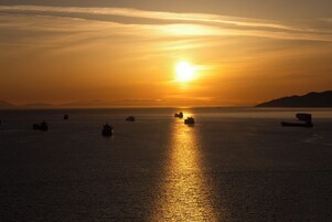 A sunset over a calm sea with several ships.