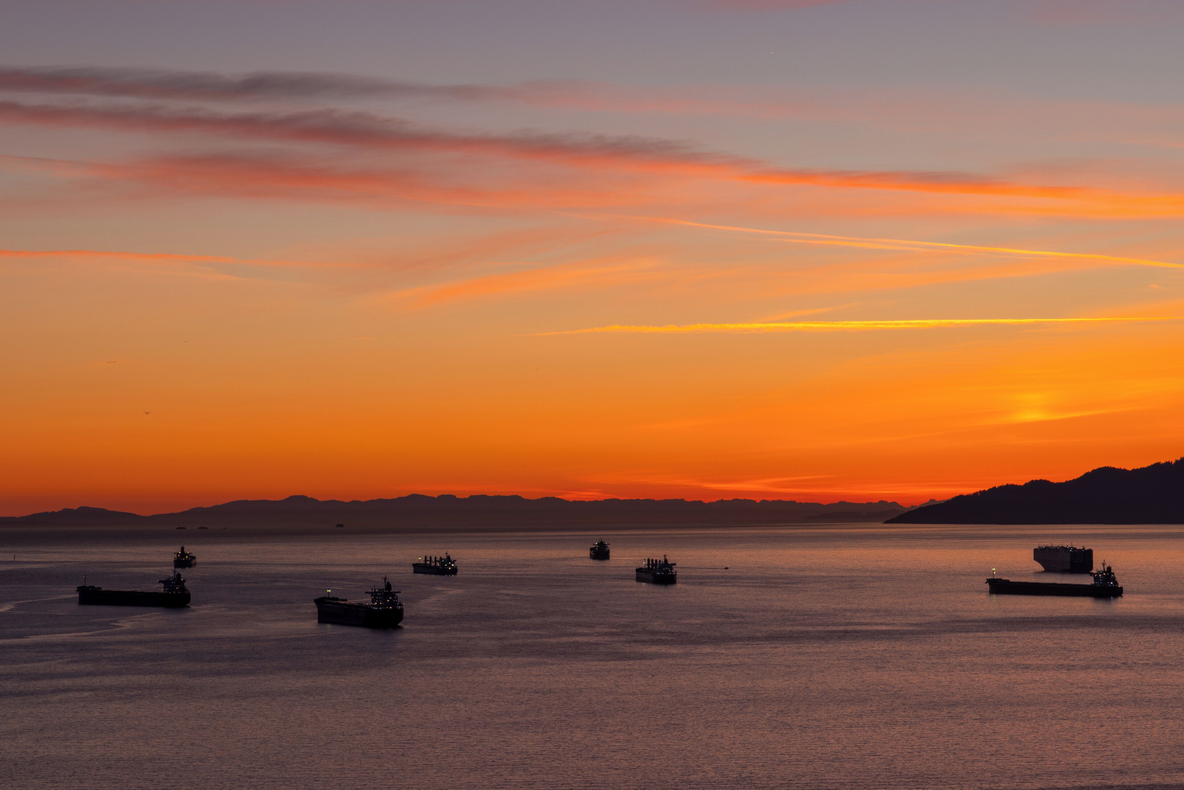 A sunset over a calm body of water with several ships.