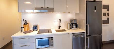 A modern kitchen with white cabinetry, stainless steel appliances, a built-in oven, and a dishwasher.