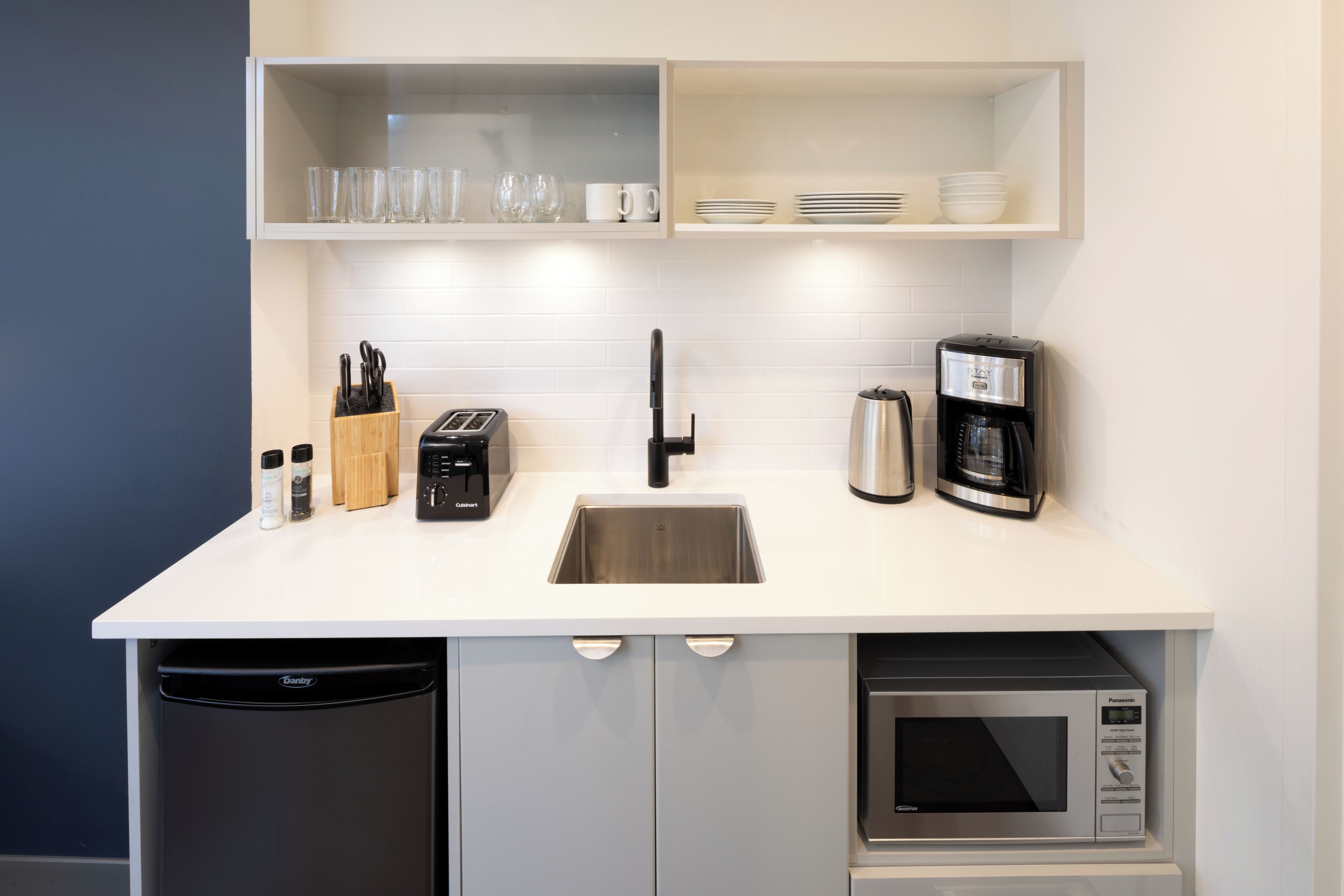 A modern kitchen with a dishwasher, microwave, coffee maker, toaster, and knife block.
