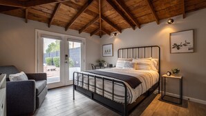 Ein Schlafzimmer mit einem Bett, einem Schlafsofa, einem kleinen Tisch und einer Tür, die auf einen Balkon führt.