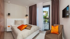 Ein Hotelzimmer mit Bett, Sessel, Fernseher und einem Balkon mit Blick.