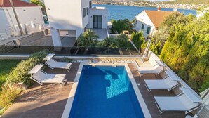 Eine moderne Villa mit Swimmingpool, weißen Wänden und Meerblick.