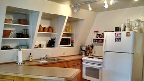 Une cuisine avec des meubles de rangement en bois, un réfrigérateur blanc, une cuisinière et divers appareils de cuisine.