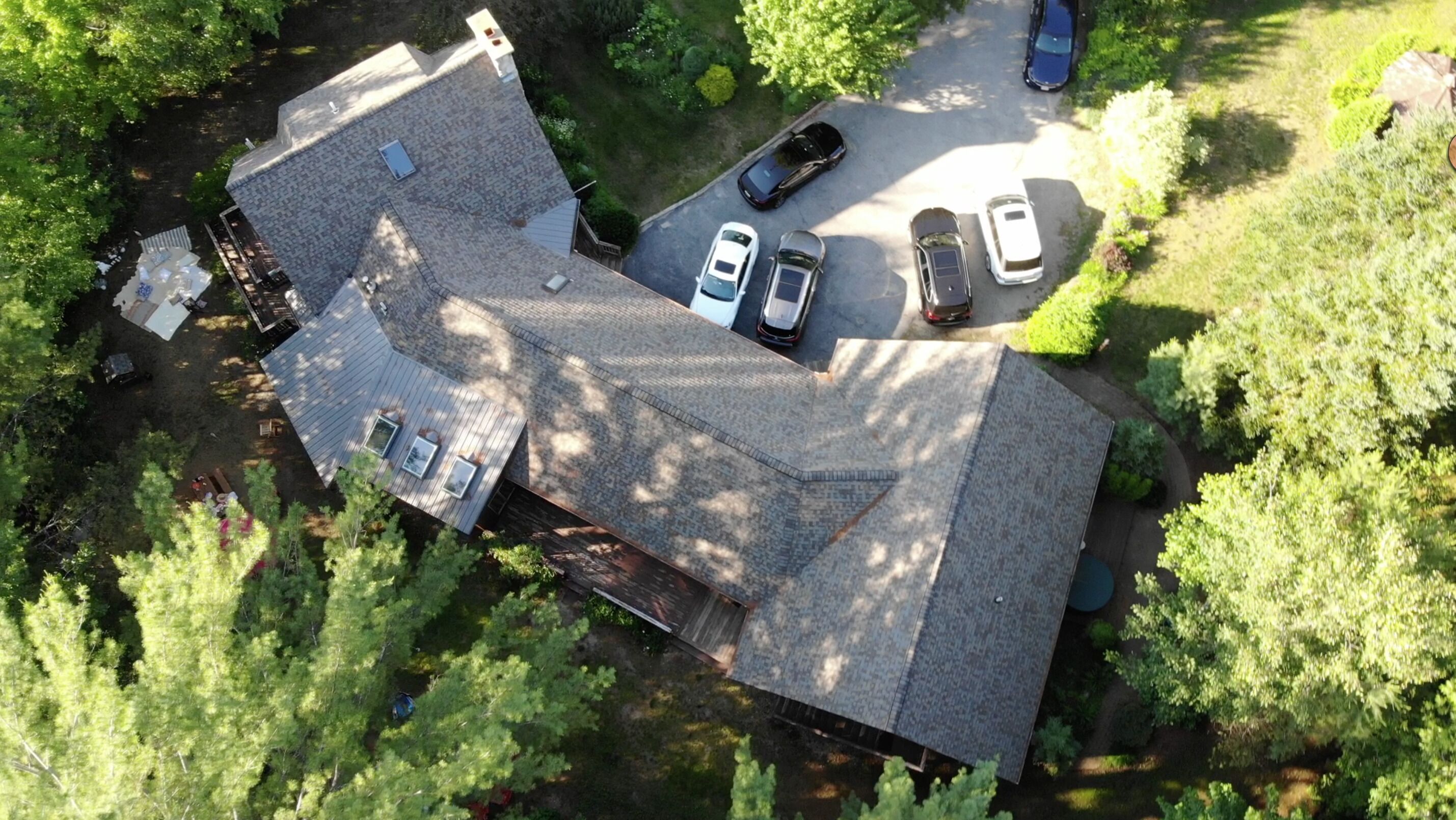 Ein Luftbild eines Wohngebiets mit einem Haus, einer Auffahrt und parkenden Autos.