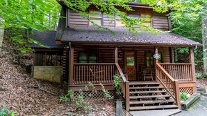 Eine zweistöckige Blockhütte mit Veranda und Steinunterbau.
